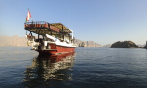 Potápěčská loď kotví na klidném moři u skalnatého pobřeží za jasného počasí.