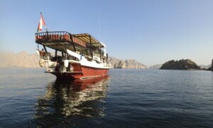 Potápěčská loď kotví na klidném moři u skalnatého pobřeží za jasného počasí.